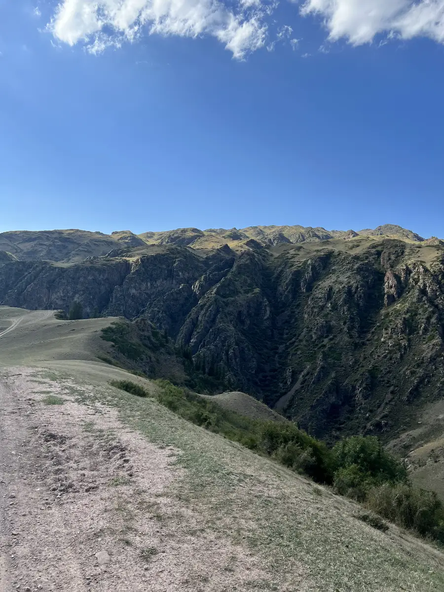 Dirt road running along the edge of a deep rocky gorge on the Assy Plateau